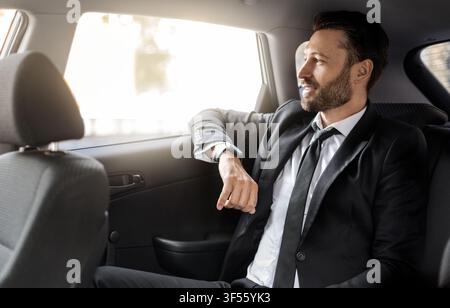 Successful businessman looking through window at car Stock Photo