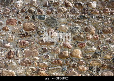 Old fieldstone wall background texture. Traditional European rustic stone masonry close up. Stock Photo