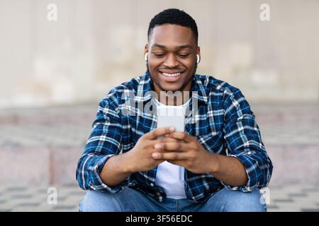 Portrait of guy listening to music and texting on phone Stock Photo