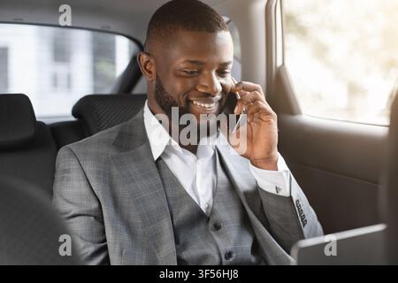 Smiling black businessman having conversation on smartphone Stock Photo