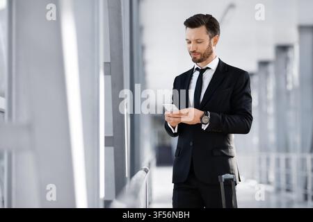Smiling businessman texting his lover while waiting for departure Stock Photo