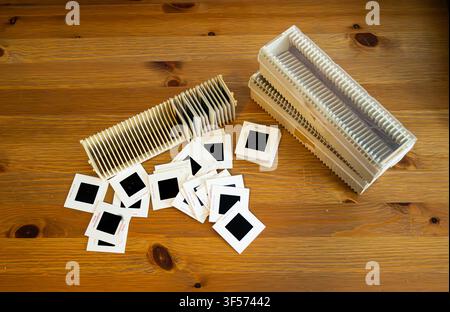 White slide film strips lie scattered on a wooden table. Two wooden slide holders rest beside them. The scene suggests nostalgia or vintage photo edit Stock Photo