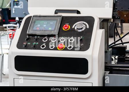 Industrial control panel with touchscreen display and toggle switches, featuring clean white design, prominent red emergency stop button, functional u Stock Photo