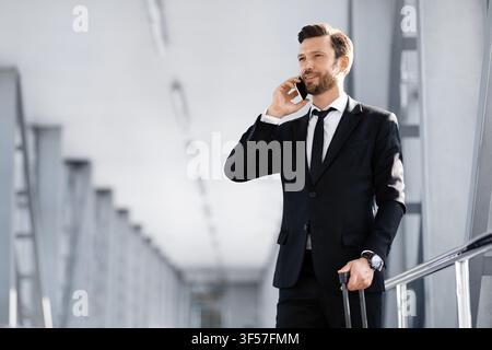 Handsome businessman standing in airport, talking on phone Stock Photo