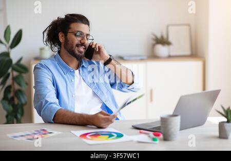 Western Man Freelance Designer Talking On Cellphone With Client, Discussing Future Project Stock Photo