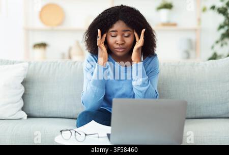 Tired african american lady touching and massaging temples Stock Photo