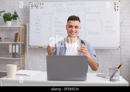 Fun english lessons remotely and tutor during coronavirus outbreak. happy guy gesturing and explaining English rules for students and looking at Stock Photo