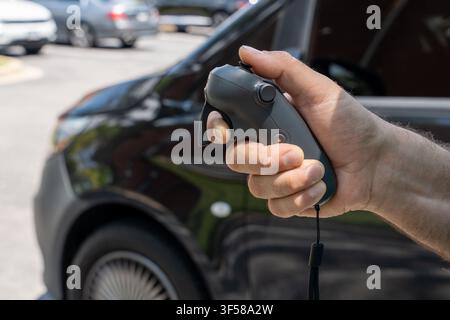 Man's hand holding a compact drone remote controller outdoors. Concept of aerial photography, remote piloting, travel, innovation Stock Photo