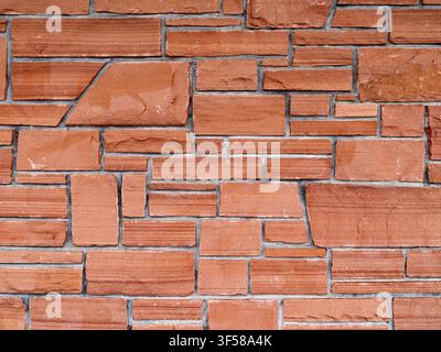 The abstract surface of an exterior wall made of irregularly shaped red stones Stock Photo