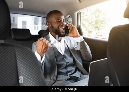 Delighted african entrepreneur having pleasant conversation on phone in car Stock Photo