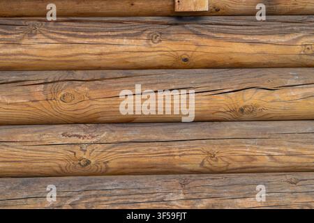 Wooden beams and logs are placed side by side to create walls for buildings. These structures are common in rural places surrounded by trees. Stock Photo