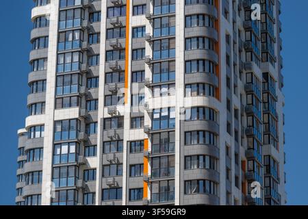 A tall building stands proudly, featuring a blend of sleek glass and colorful accents. Sunlight reflects off the windows, enhancing its striking desig Stock Photo