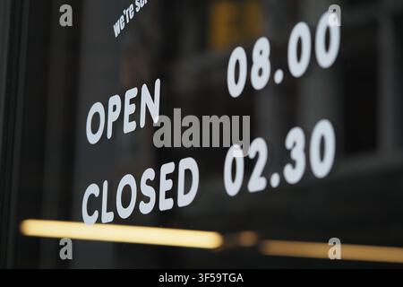 Store hours displayed on a window in the city Stock Photo