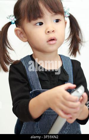 Japanese girl using remote controller (3 years old) Stock Photo
