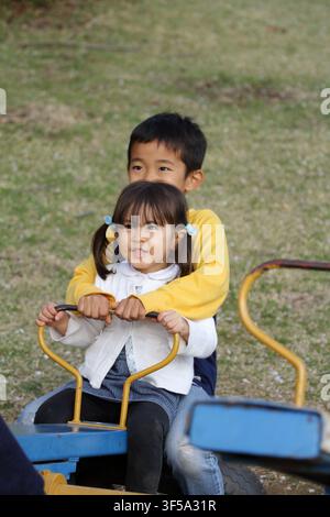 Japanese brother and sister on the seesaw (8 years old boy and 3 years old girl) Stock Photo