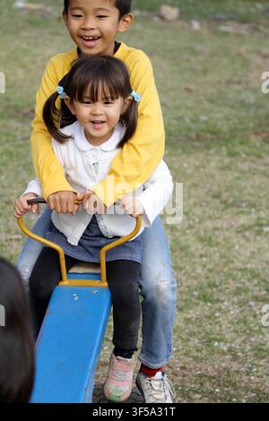 Japanese brother and sister on the seesaw (8 years old boy and 3 years old girl) Stock Photo