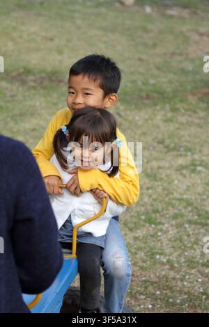 Japanese brother and sister on the seesaw (8 years old boy and 3 years old girl) Stock Photo