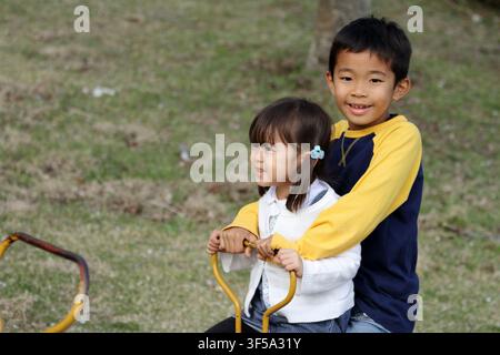 Japanese brother and sister on the seesaw (8 years old boy and 3 years old girl) Stock Photo
