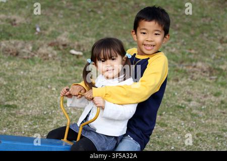 Japanese brother and sister on the seesaw (8 years old boy and 3 years old girl) Stock Photo