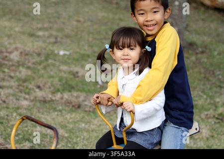 Japanese brother and sister on the seesaw (8 years old boy and 3 years old girl) Stock Photo