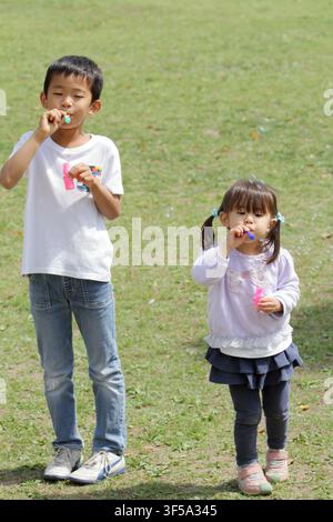 Japanese brother and sister playing with bubble (8 years old boy and 3 years old girl) Stock Photo
