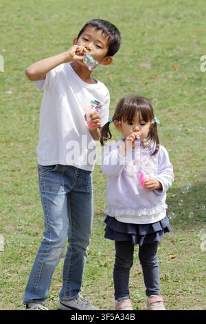 Japanese brother and sister playing with bubble (8 years old boy and 3 years old girl) Stock Photo