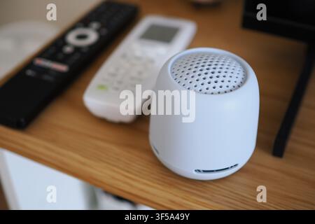 Small speaker on a wooden table next to remote controls Stock Photo
