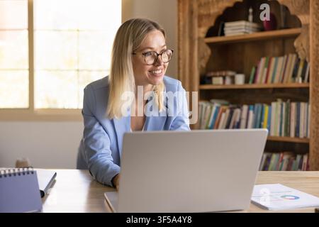 Focused older adult businesswoman working on laptop at workplace desk Stock Photo