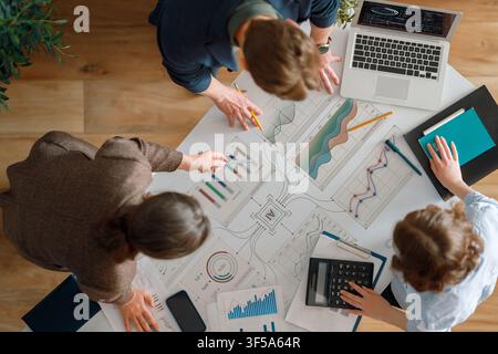 Dynamic overhead view of a diverse business team collaborating on financial charts and analytics. This image captures a professional workspace filled Stock Photo