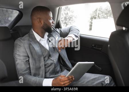 Thoughtful black guy entrepreneur using digital tablet in car Stock Photo