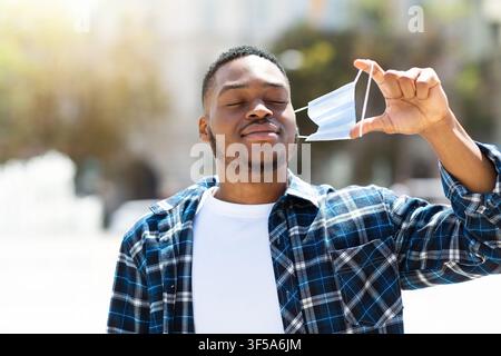 Portrait of afro man taking off mask and breathing Stock Photo
