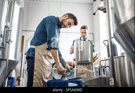 Two Young Men Working In Kitchen Preparing Ingredients For Cooking, Focused Action Stock Photo