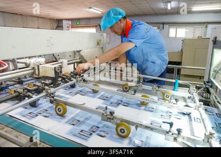 Luanan, China - July 30, 2026: Worker Debugging Laminating Machinery in Printing Workshop Stock Photo