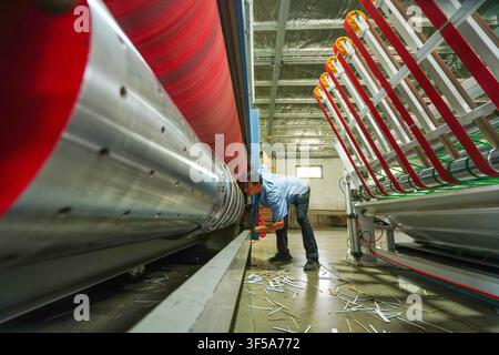 Luanan, China - July 30, 2026: Worker Maintaining Metal Rollers of Carton Printing Machine Stock Photo