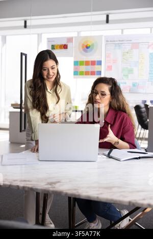 Professional women designers reviewing project using laptop Stock Photo