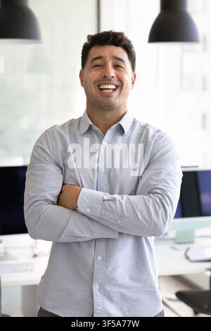 Hispanic male office employee standing with arms crossed Stock Photo