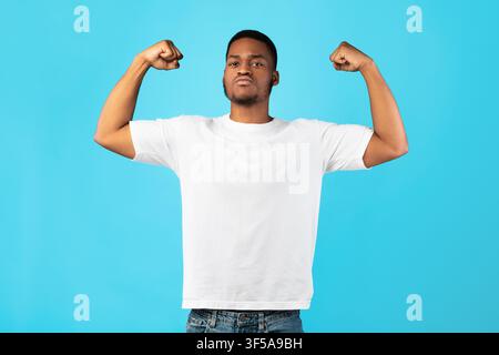 Strong Black Guy Showing Biceps Posing On Blue Background Stock Photo