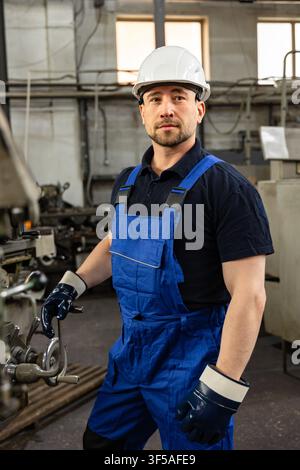 Industrial worker operating machine in modern manufacturing workshop wearing safety equipment Stock Photo