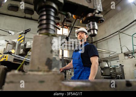 Industrial worker operating metalworking machine in modern manufacturing factory Stock Photo