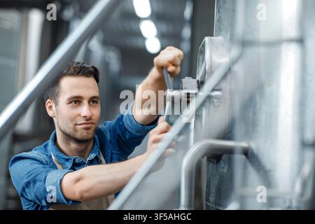 Focused Young Caucasian Man Operating Machinery In Industrial Setting, Healthcare Concept Stock Photo