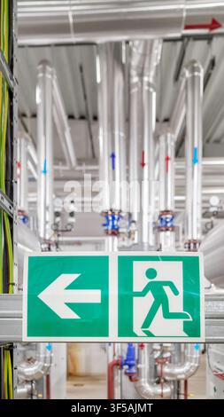 Industrial emergency exit sign with a directional arrow inside a district heating plant, selective focus. Stock Photo
