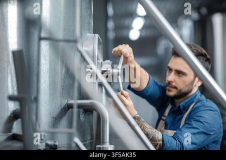 Focused Caucasian Male Technician Adjusting Machinery In Industrial Setting Stock Photo