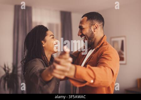 Happy Black Couple Enjoying Dancing Together At Home, Close Up Lifestyle Moment Stock Photo
