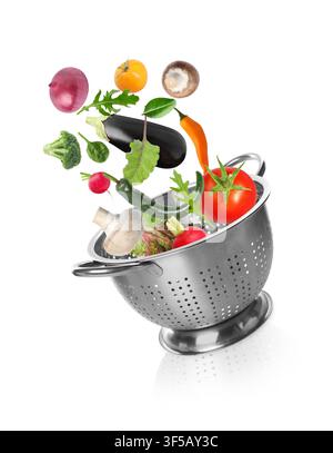 Fresh vegetables and colander in air on white background Stock Photo