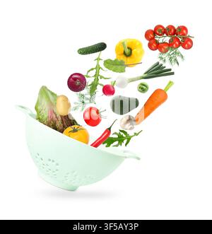 Fresh vegetables and colander in air on white background Stock Photo