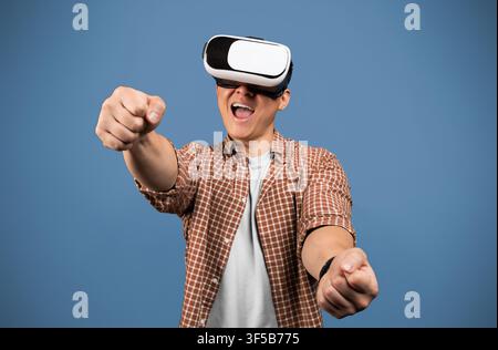Excited Young Man With Vr Headset Engaging In Virtual Reality Experience, Studio Background Stock Photo