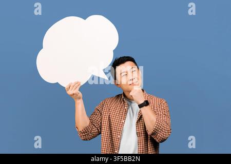 Thoughtful Asian Man Holding Speech Bubble And Thinking, Creative Concept Stock Photo