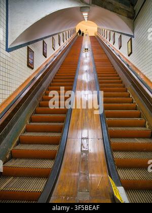 Antwerp, Belgium - Apr 12 2026: Symmetrical wooden escalators rise through the tiled Sint Annatunnel in Antwerp Belgium with warm light and vintage urban character Stock Photo
