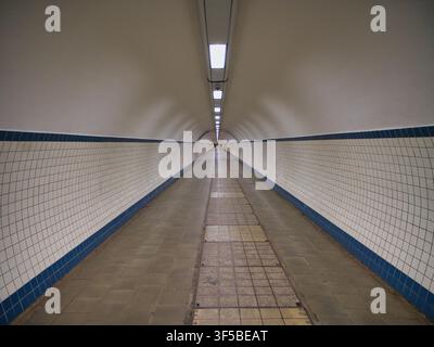 Antwerp, Belgium - Apr 12 2026: Long tiled passage and glowing ceiling lights create dramatic perspective inside Sint Annatunnel in Antwerp Belgium Stock Photo