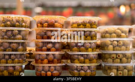 Stacked plastic tubs of marinated olives at a market stall, close-up food display — concept: Mediterranean deli food, market produce, food packaging, Stock Photo